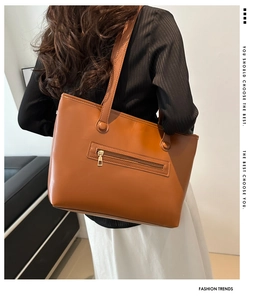 Dettaglio borsa tote in pelle color cuoio con tasca frontale dorata con cerniera e tracolla