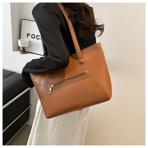 Borsa tote in pelle marrone indossata a spalla, evidenziando capienza e dettagli zip