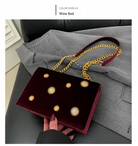 Nahaufnahme der weinroten Samttasche mit goldenen Sonnen-Nieten und schicker Metallkette