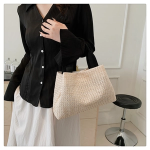 Close-up of straw woven tote bag with black strap showing fine texture and large capacity