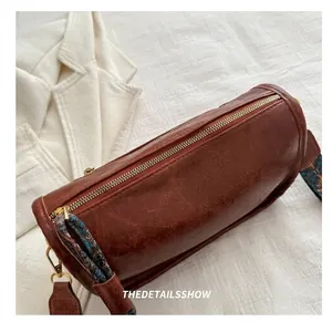 Détail du sac Boston marron avec texture grainée et bandoulière tissée ethnique