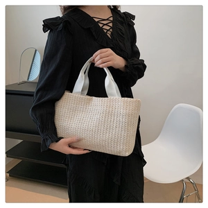 Close-up of cream woven straw handbag with fabric handles in a minimalist interior setting