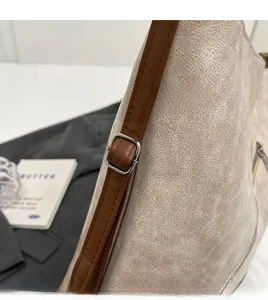 Detail of adjustable brown leather shoulder strap on a beige vintage texture tote bag