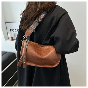 Detail of brown leather tote with ethnic patterned wide strap and decorative tassel