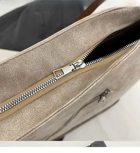 Close-up of smooth silver metal zipper and vintage textured beige leather bag detail
