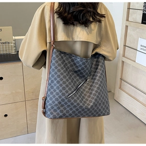 Detail of a large geometric pattern tote bag with brown leather straps on a khaki trench coat