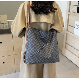 Detail of a large crossbody tote with geometric patterns worn with a trench coat