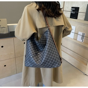Detail of grey patterned tote bag featuring a diagonal zipper pocket and slim straps