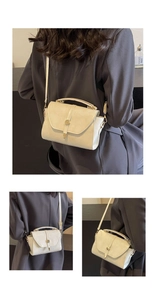 Détails du sac bandoulière crème en cuir avec boucle dorée sur un blazer gris chic