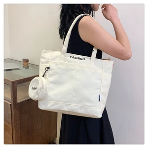 Detalle de bolsa tote de lona blanca con bolsillo lateral y estuche redondo con cremallera
