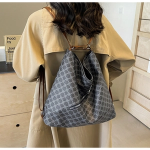 Detail of grey patterned tote bag with brown straps worn with a beige trench coat