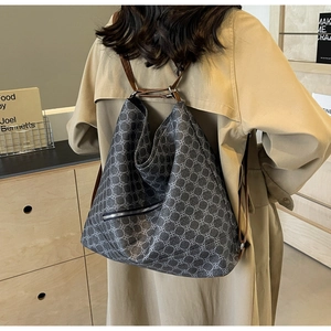 Deep grey clover pattern multifunctional bag shown as a shoulder bag on a beige coat