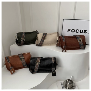 Five cylindrical leather crossbody bags with colorful ethnic style patterned straps on display