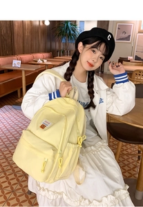 Modella asiatica con zaino giallo in un caffè, mostra la vestibilità reale e lo stile casual