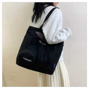 Detalle de bolso tote de lona negra con gran capacidad y pequeño monedero colgante