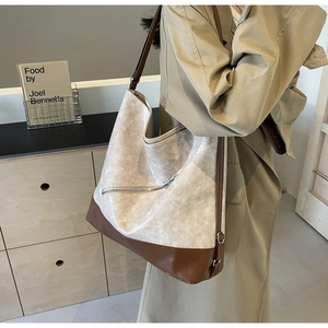 Detail of a large beige and brown tote bag showing the lychee leather texture and metal zipper