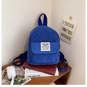 Macro-opname van blauwe corduroy mini-rugzak met wit logo-label op een houten plank