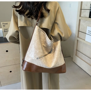 Detail of large tote bag with beige wrinkled texture and brown leather base shown on model