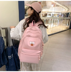 Dettaglio zaino scuola rosa con tasche multiple a cerniera ed etichetta in tessuto