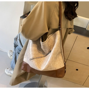 Detail of a large two-tone patchwork tote bag with stylish diagonal zipper worn by a model