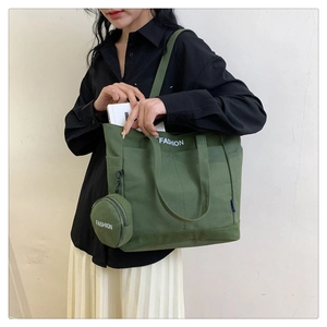 Detalle del bolso tote de lona verde oscuro con monedero a juego y texto blanco impreso