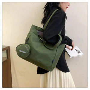 Detalle del bolso tote de lona verde oliva con bolsillo lateral y monedero redondo colgado