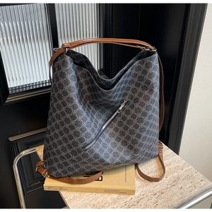 Detailed view of the large tote bag featuring clover patterns and contrasting brown leather straps