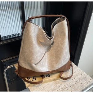 Close-up of dual-use tote bag featuring two-tone grey and brown leather with zipper detail