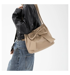 Detail der aprikosenfarbenen Schultertasche mit großer Schleife und matter Lederstruktur