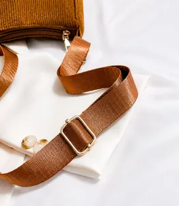 Detail view of smooth brown corduroy fabric with adjustable nylon strap and gold buckle