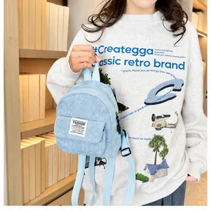 Detail of light blue corduroy mini backpack with front pocket and fabric label tag