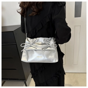 Macro detail of silver tote bag featuring chic bow accents and ruched flap design