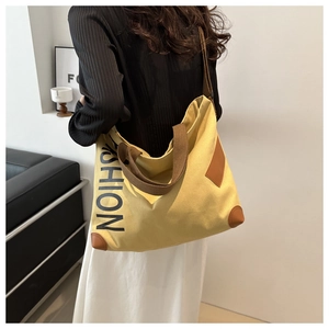 Détail du grand sac cabas jaune en toile avec anses brunes et inscription FASHION