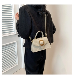 Détail du sac crème avec boucle dorée sur cuir mat texturé porté à l'épaule