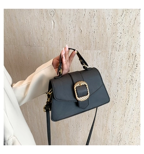 Détail du sac à main trapèze noir avec boucle métallique dorée et poignée supérieure