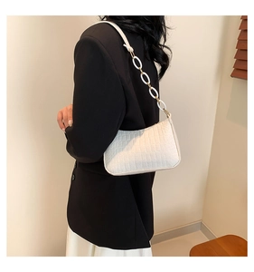 Detail of white crocodile texture baguette bag with resin chain strap on shoulder