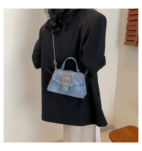 Detail view of light blue retro shoulder bag with golden buckle on model
