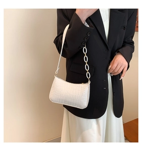White crocodile pattern baguette bag with stylish metal chain on a female model