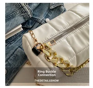 Close-up of white quilted leather bag featuring a chunky gold chain and textured zipper