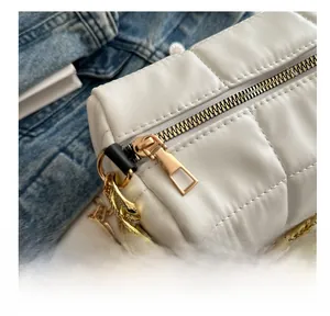 Close-up of golden metal zipper and thick chain detail on a white quilted pillow bag