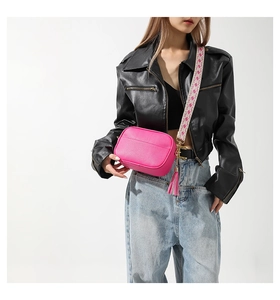 Detail of hot pink leather crossbody bag featuring a wide geometric pattern strap