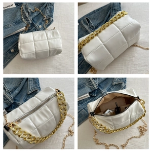Detail view of white quilted crossbody bag with gold chain and metal zipper closure
