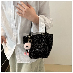 Détail d'un sac à main pailleté noir avec chaîne métal et breloque en peluche