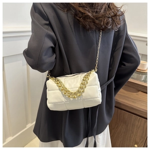 Detail of white quilted pillow bag with chunky gold chain handle on a model shoulder