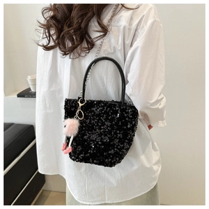 Détail du sac à main en paillettes noires avec chaîne métallique et breloque peluche rose