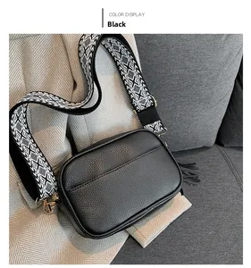 Black litchi grain messenger bag with geometric wide strap and fringe detail