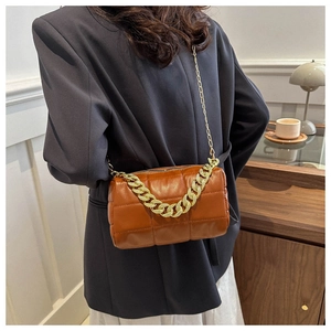 Detail of dark brown quilted crossbody bag with gold chain strap on model shoulder