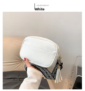 Detailed view of white crossbody bag with geometric jacquard strap and fringe tassel