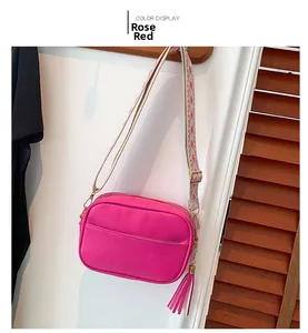 Detail of rose red crossbody bag with textured leather and geometric jacquard strap