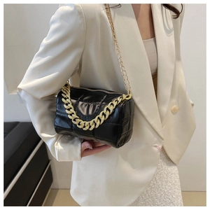 Detail of black quilted shoulder bag with chunky gold chain strap and textured leather finish
